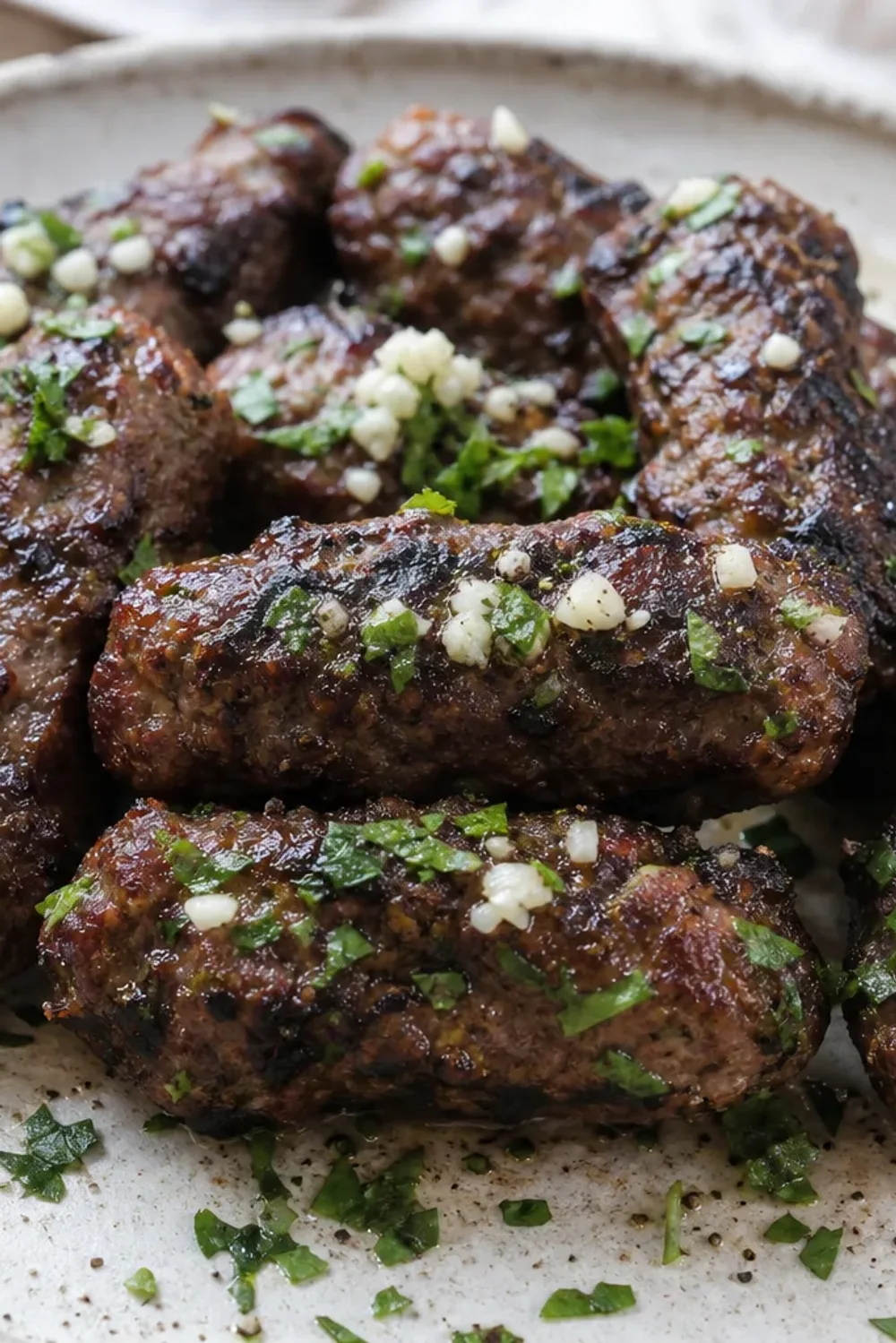 Grilled Albanian qofte served on a plate, garnished with fresh herbs and a side of vegetables.