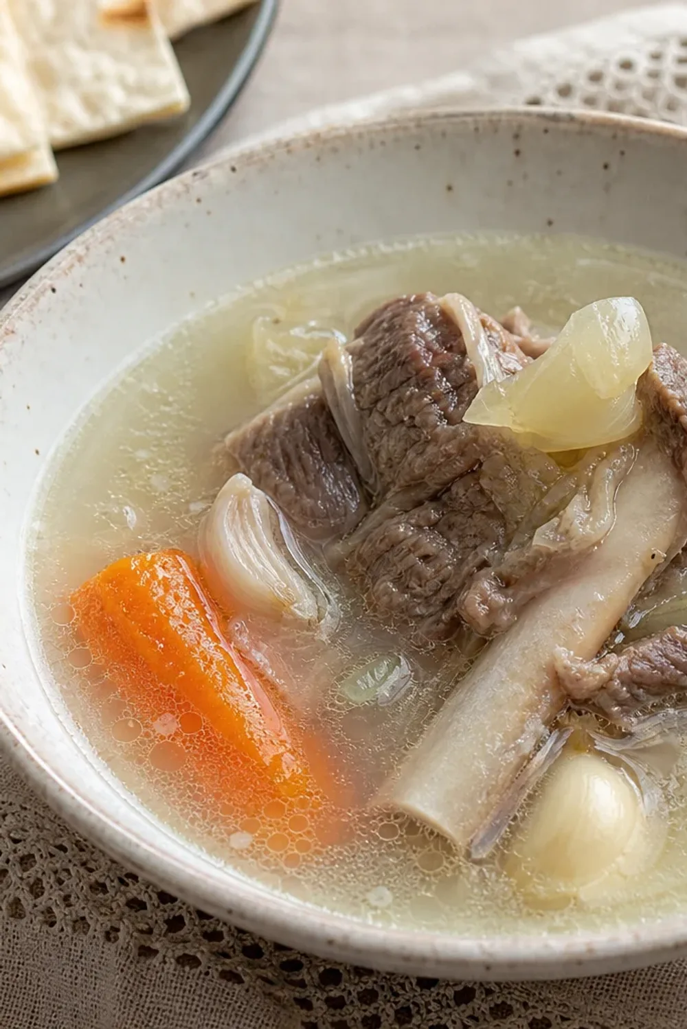 A warm bowl of Armenian Khash soup with tender meat, garlic, and crispy lavash bread.