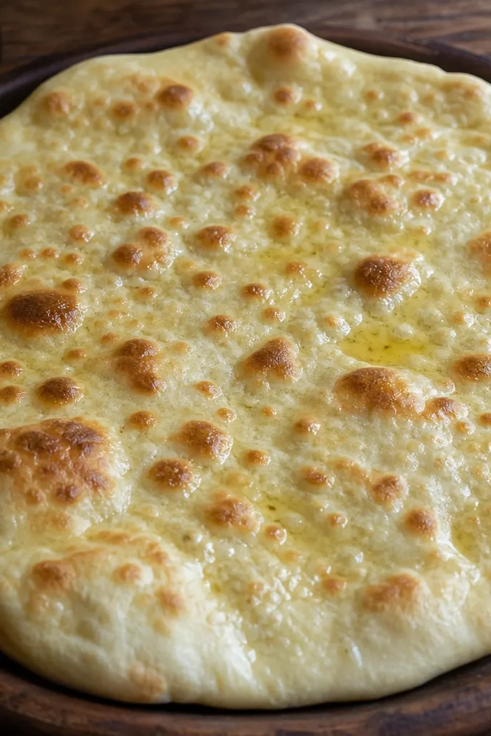 Baked Armenian lavash flatbread with a golden color and soft texture on a wooden board.