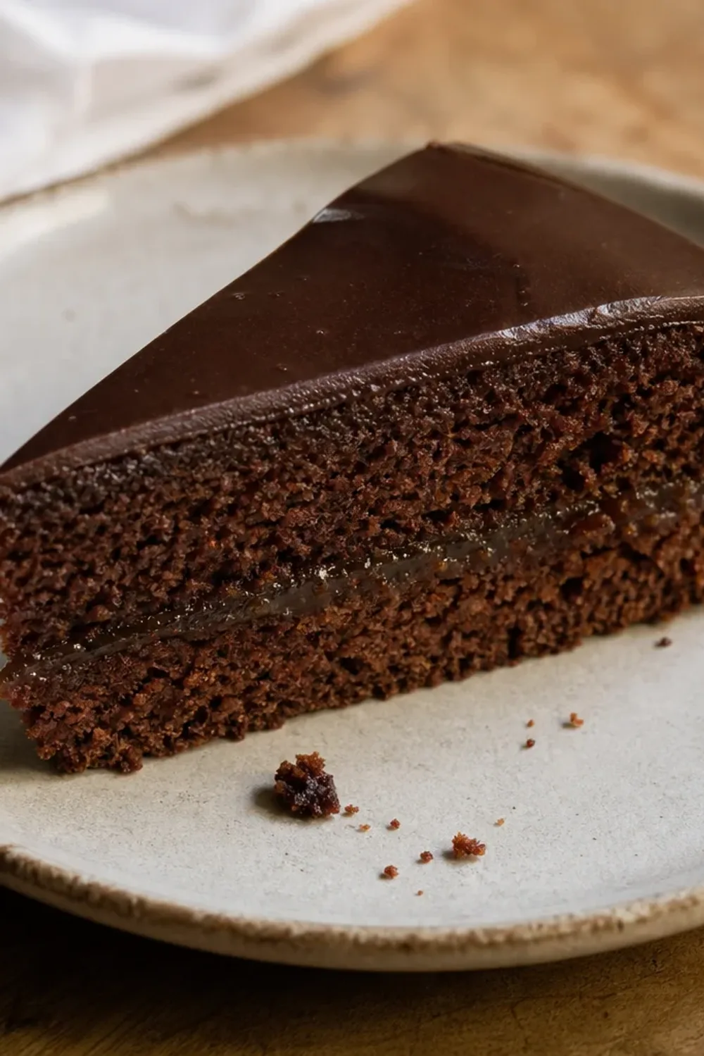 Rich chocolate layer cake with a glossy chocolate glaze and apricot jam filling, elegantly plated.