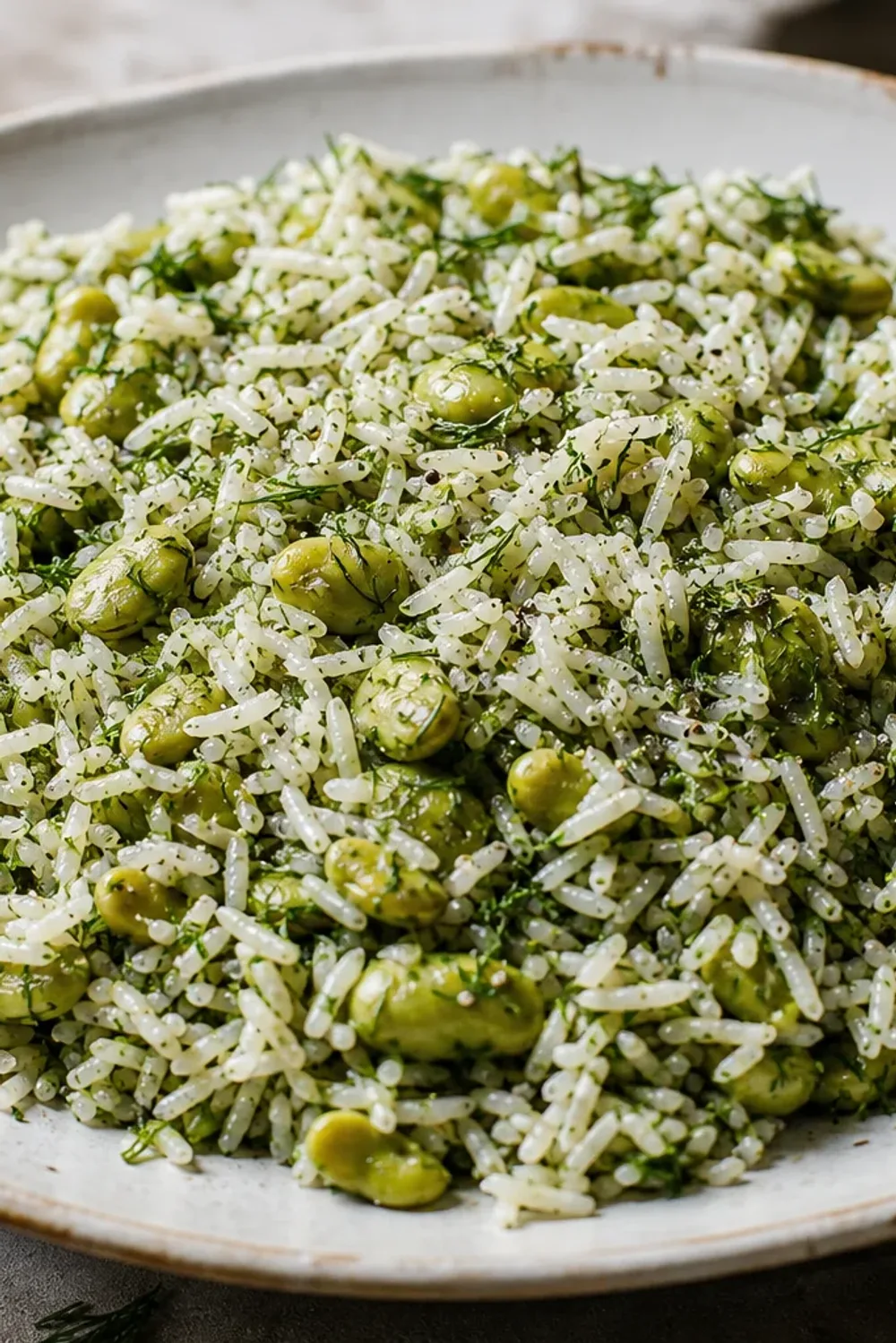 Fluffy saffron rice garnished with fresh dill and fava beans, served elegantly.