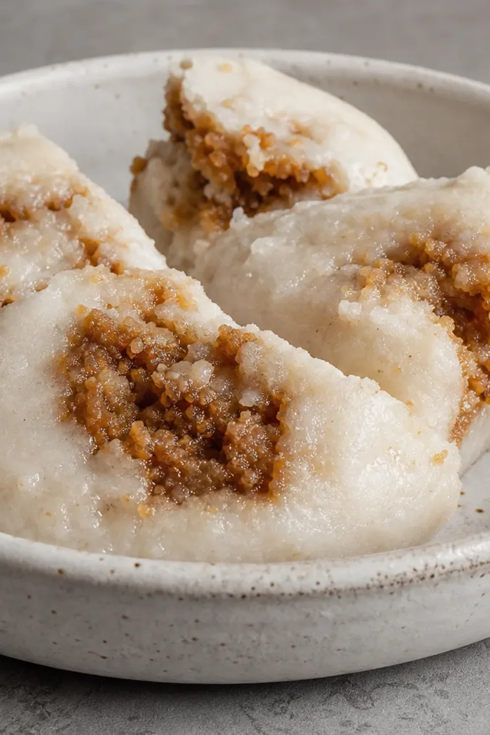 Steamed rice cakes with a golden layer of coconut and date molasses, served on a leaf.