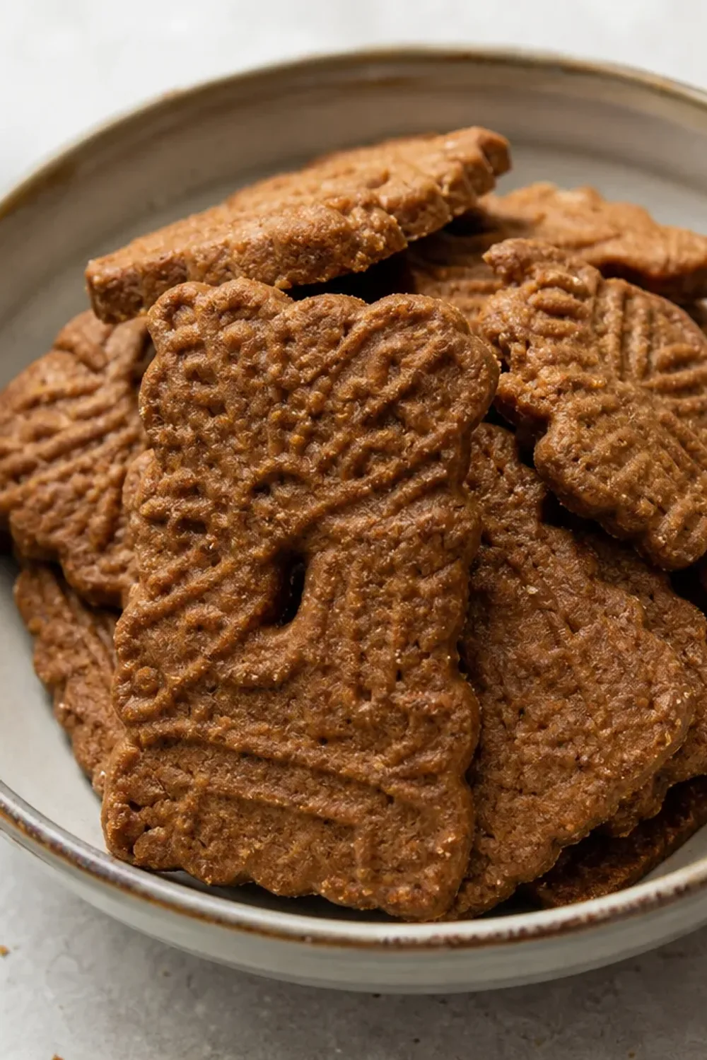 Golden-brown speculoos cookies with a spiced surface, arranged on a plate.