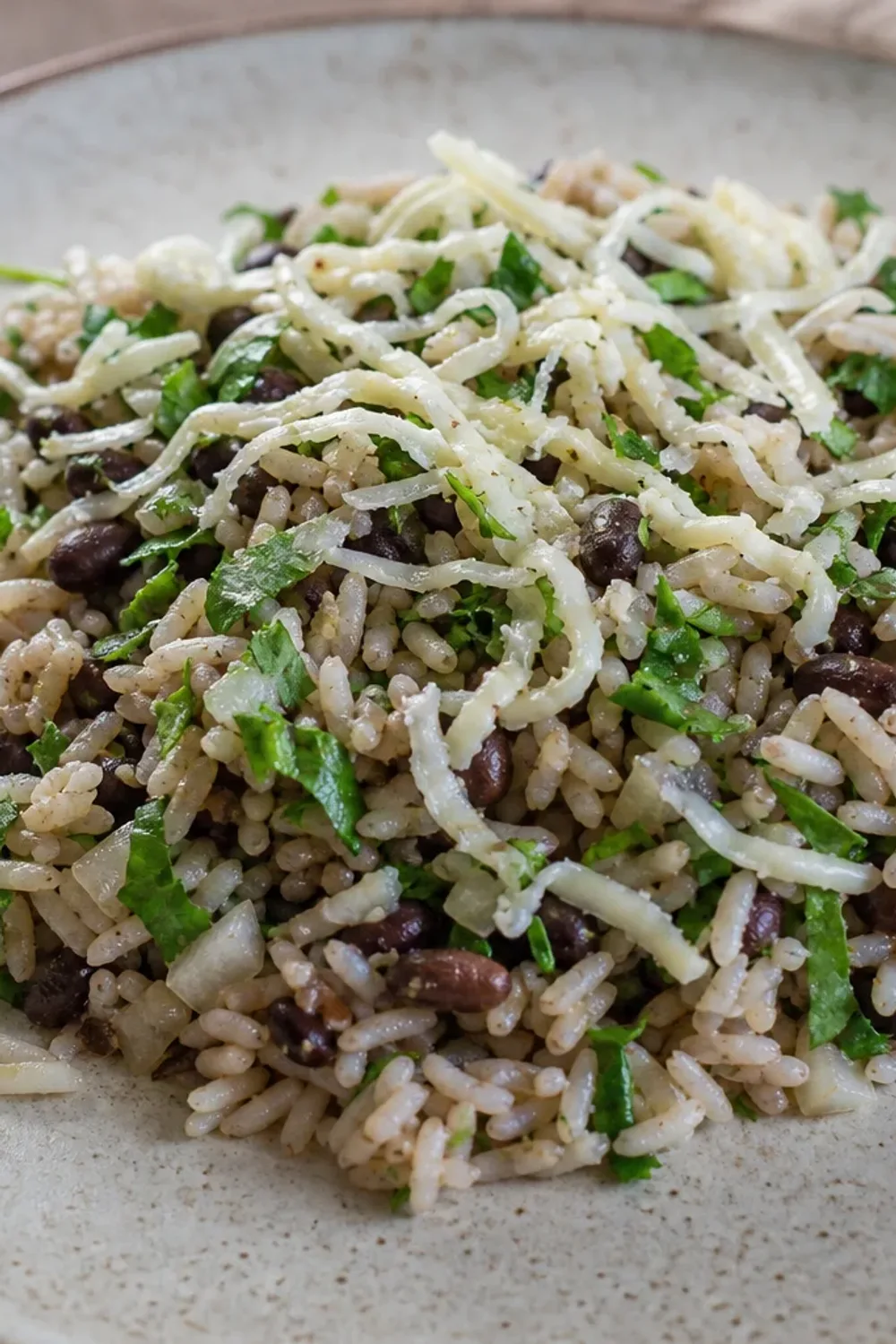 A colorful plate of Baião de Dois featuring fluffy rice, black beans, and melted cheese garnished with fresh herbs.