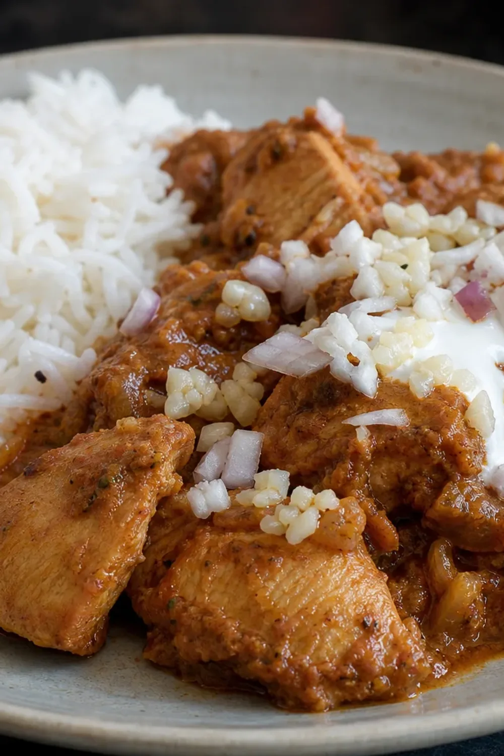A vibrant plate of chicken tikka masala with basmati rice garnished with cilantro and spices.