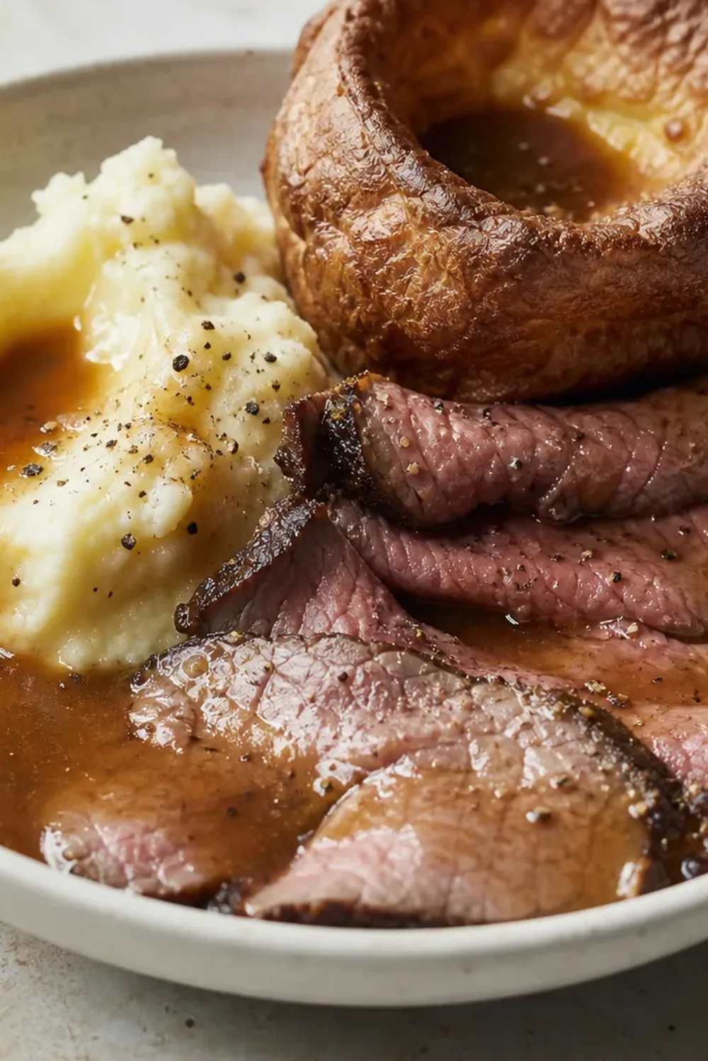 Plated roast beef with crispy Yorkshire pudding, served with gravy and vegetables.