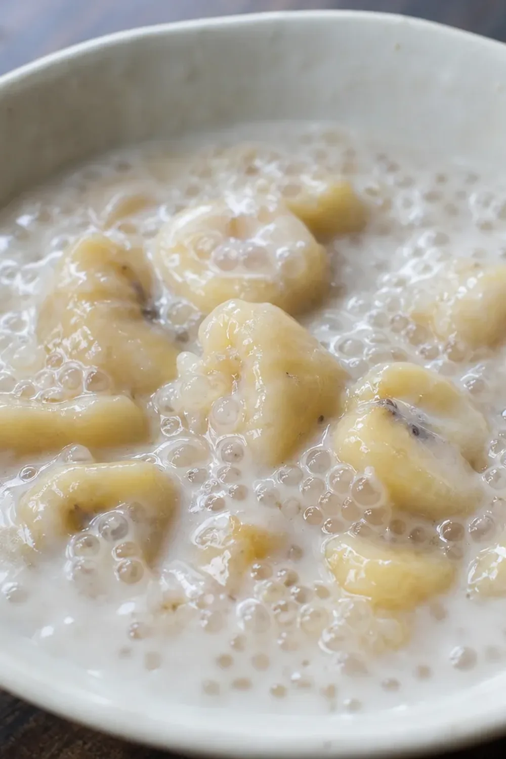 Creamy tapioca pudding layered with sliced bananas and coconut milk, garnished with toasted coconut flakes.