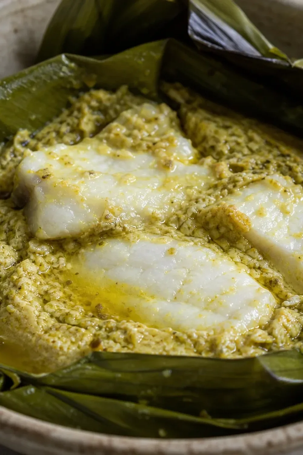 Steamed fish amok served in banana leaves, garnished with herbs and coconut milk.
