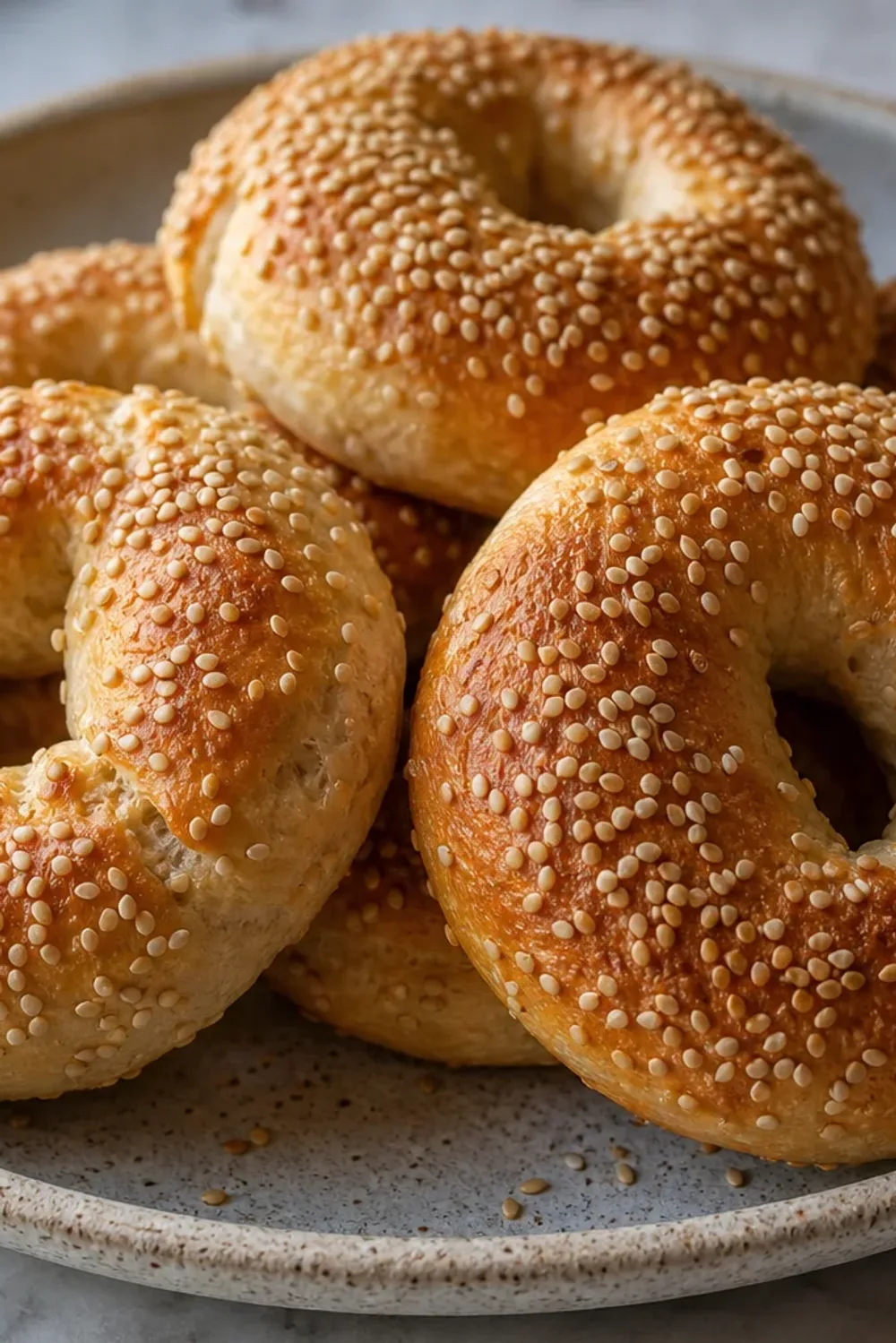 Golden brown Montreal-style bagels topped with sesame seeds, served on a wooden board.