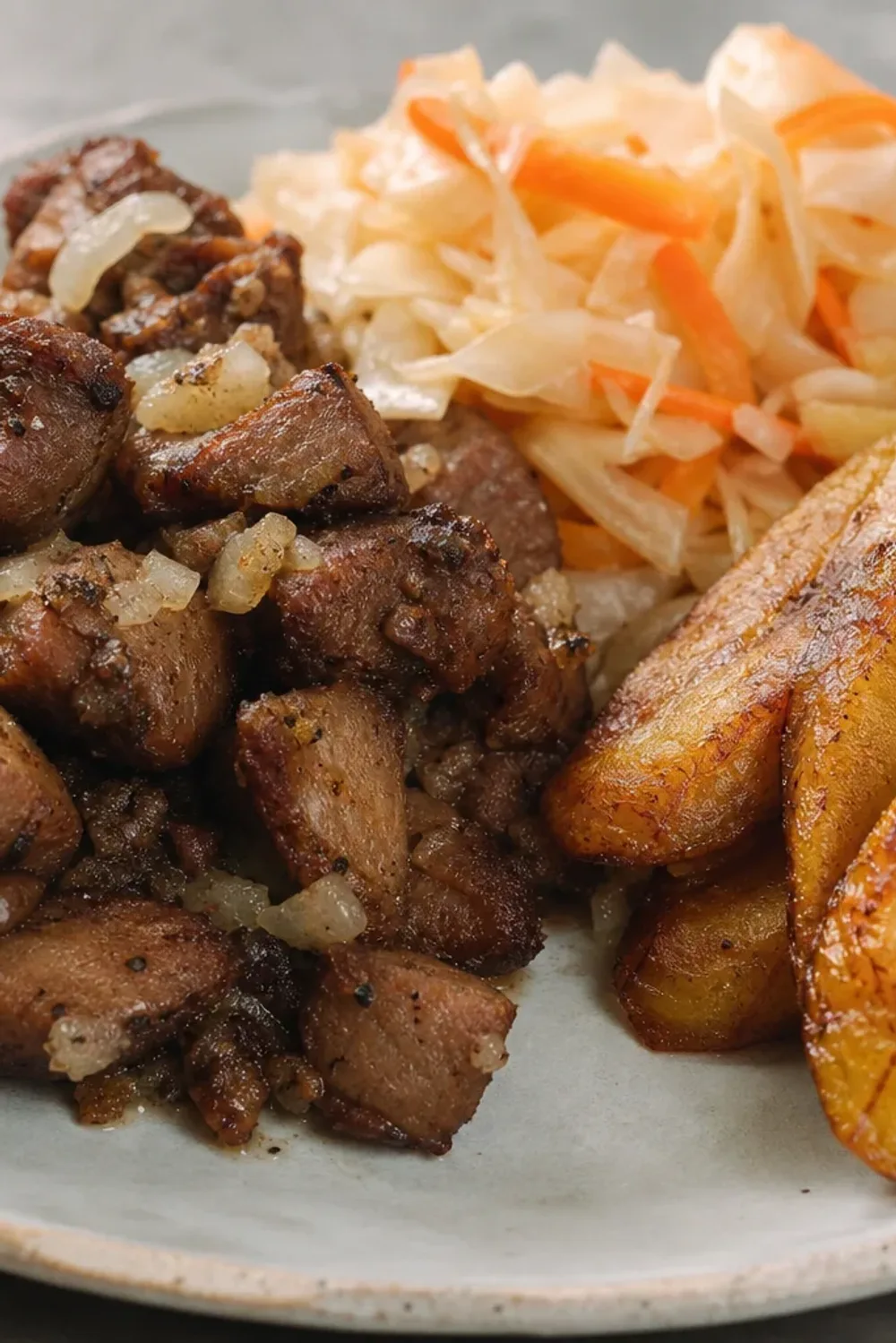 Crispy fried pork served with spicy Pikliz and golden fried plantains, garnished beautifully.