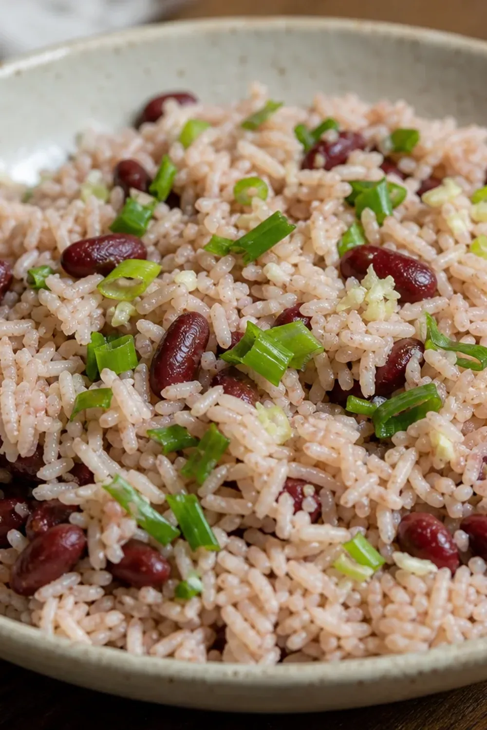 Fluffy rice and peas garnished with herbs, served in a white bowl with coconut milk texture.