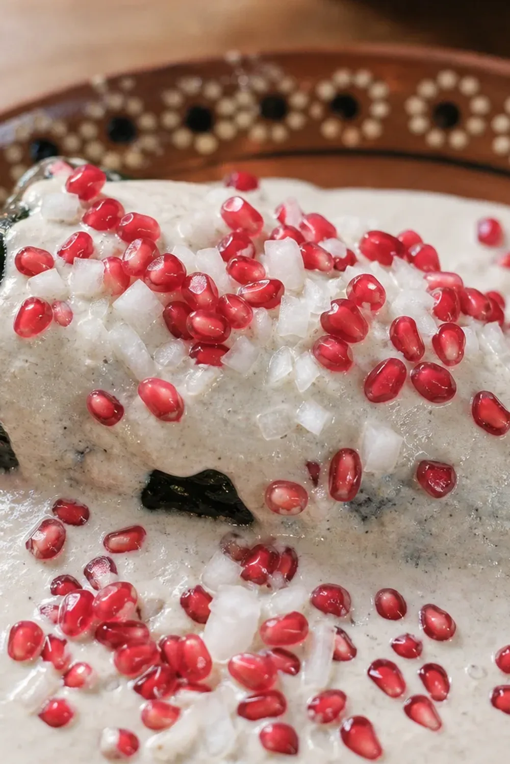 Stuffed poblano peppers topped with creamy walnut sauce and vibrant pomegranate seeds.