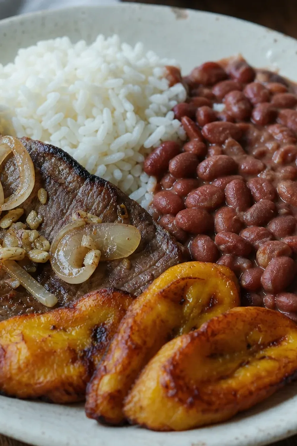 A vibrant platter of Colombian Bandeja Paisa with rice, beans, beef, and fried plantains.