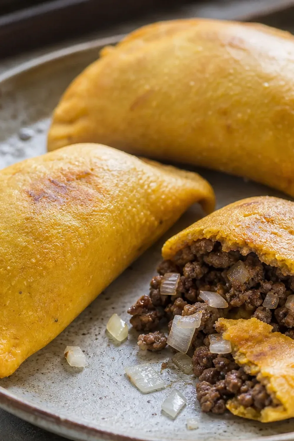 Golden-brown empanadas filled with seasoned beef, garnished and served on a plate.