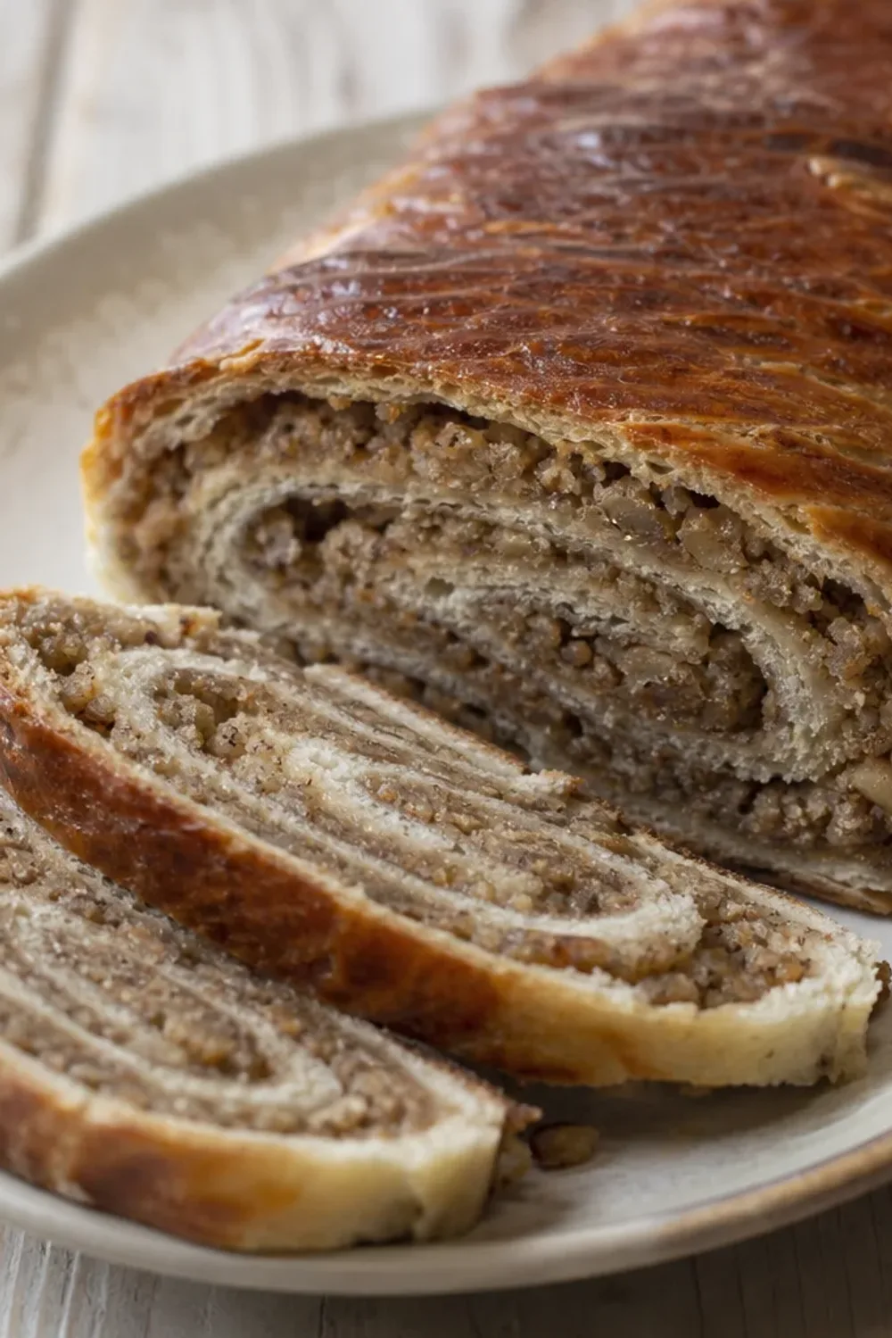 Fluffy Croatian Orahnjača roll with a golden crust, showcasing walnut and cinnamon filling.