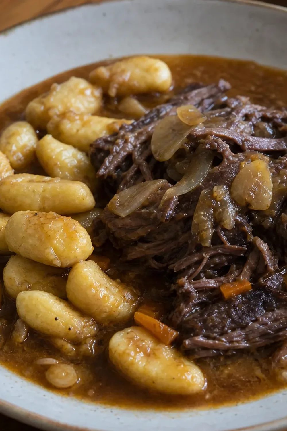 Tender beef simmered in rich red wine sauce, served with soft gnocchi and garnished with herbs.