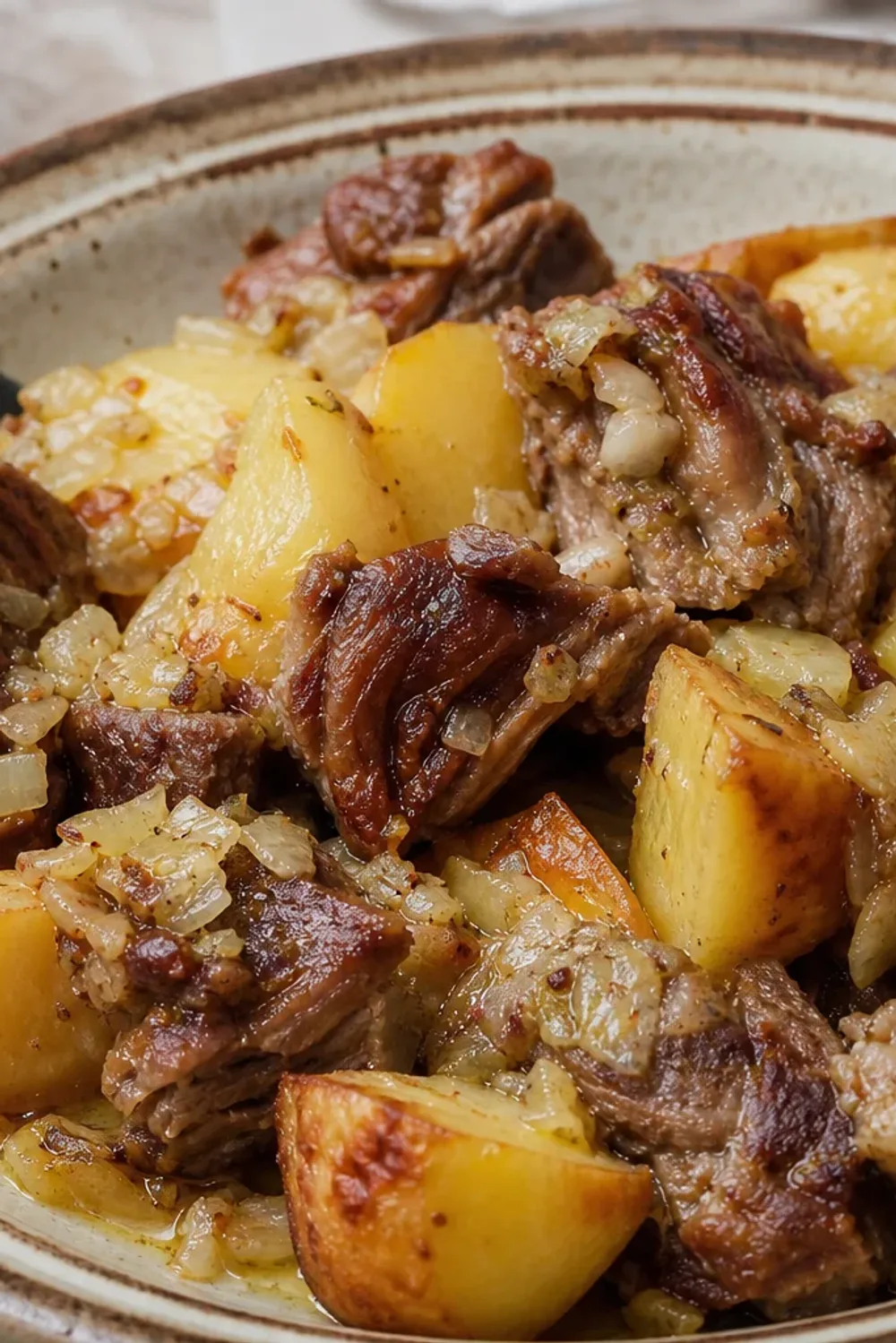Tender lamb and golden potatoes cooked with herbs, served in a rustic dish.
