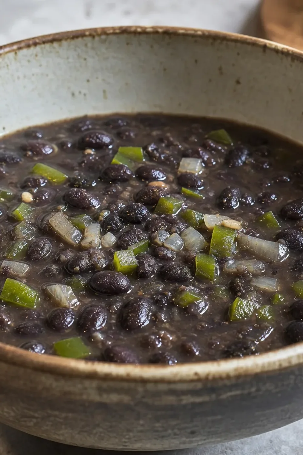 A warm bowl of Cuban black bean soup topped with fresh cilantro and lime, showcasing rich black beans and spices.
