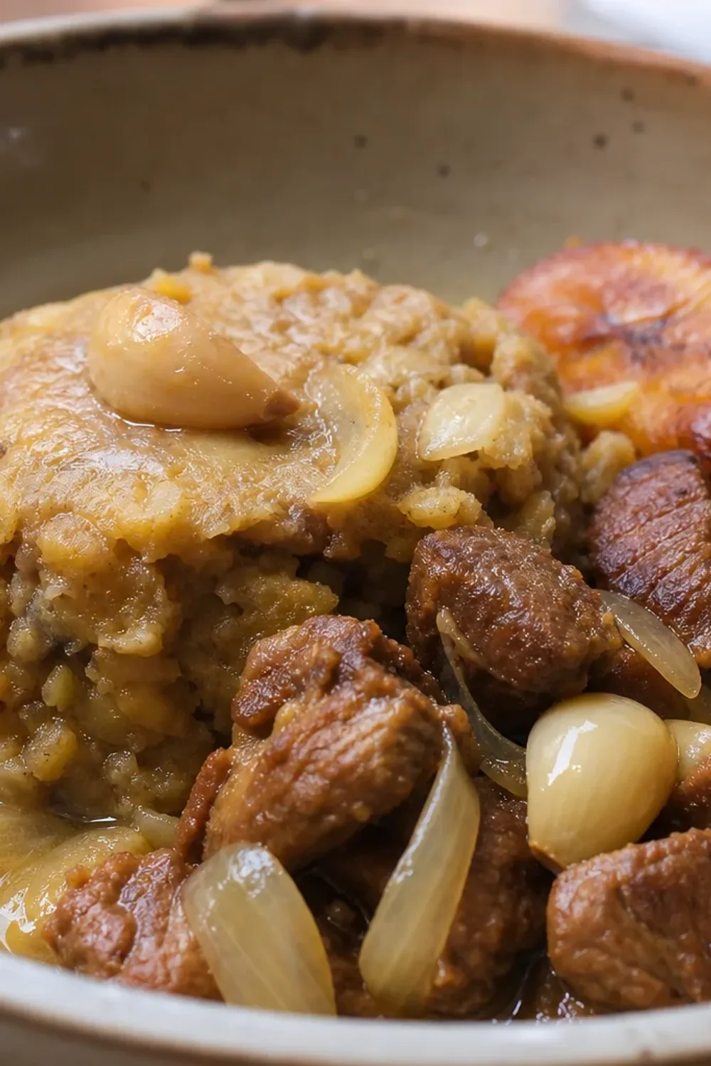 Plated Dominican mofongo with garlic pork, crispy fried plantains, and fresh herbs.