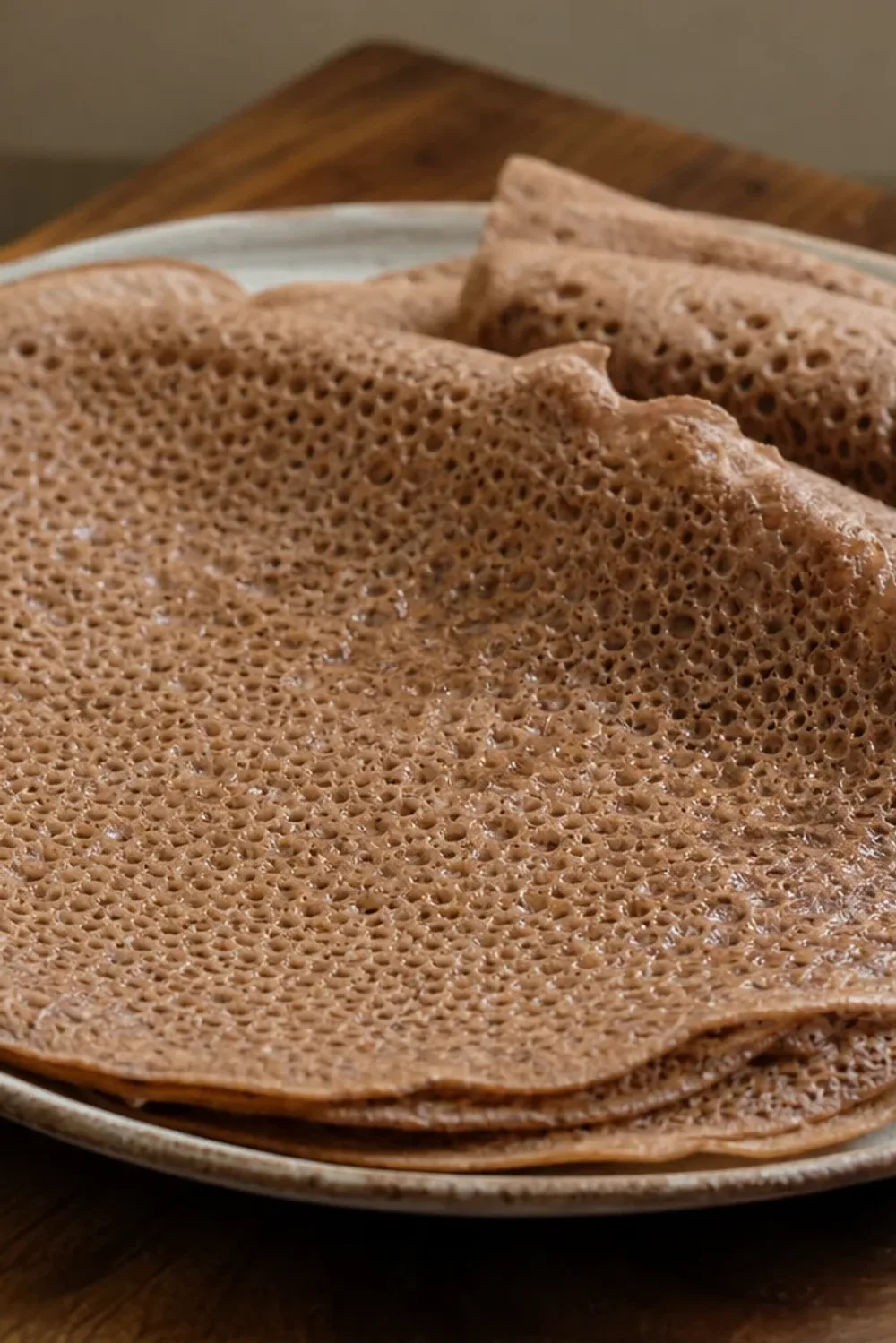 Soft and spongy injera flatbread served with colorful stews and dips, showcasing its porous texture.