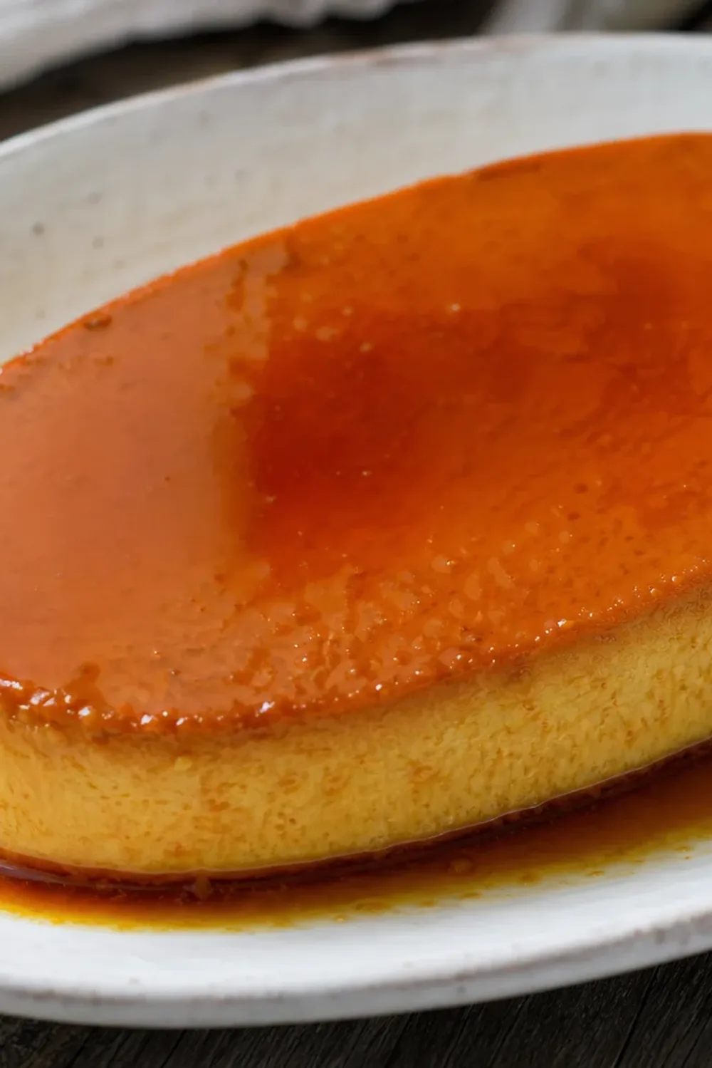 Smooth and creamy leche flan topped with glossy caramel, served in a round dish.