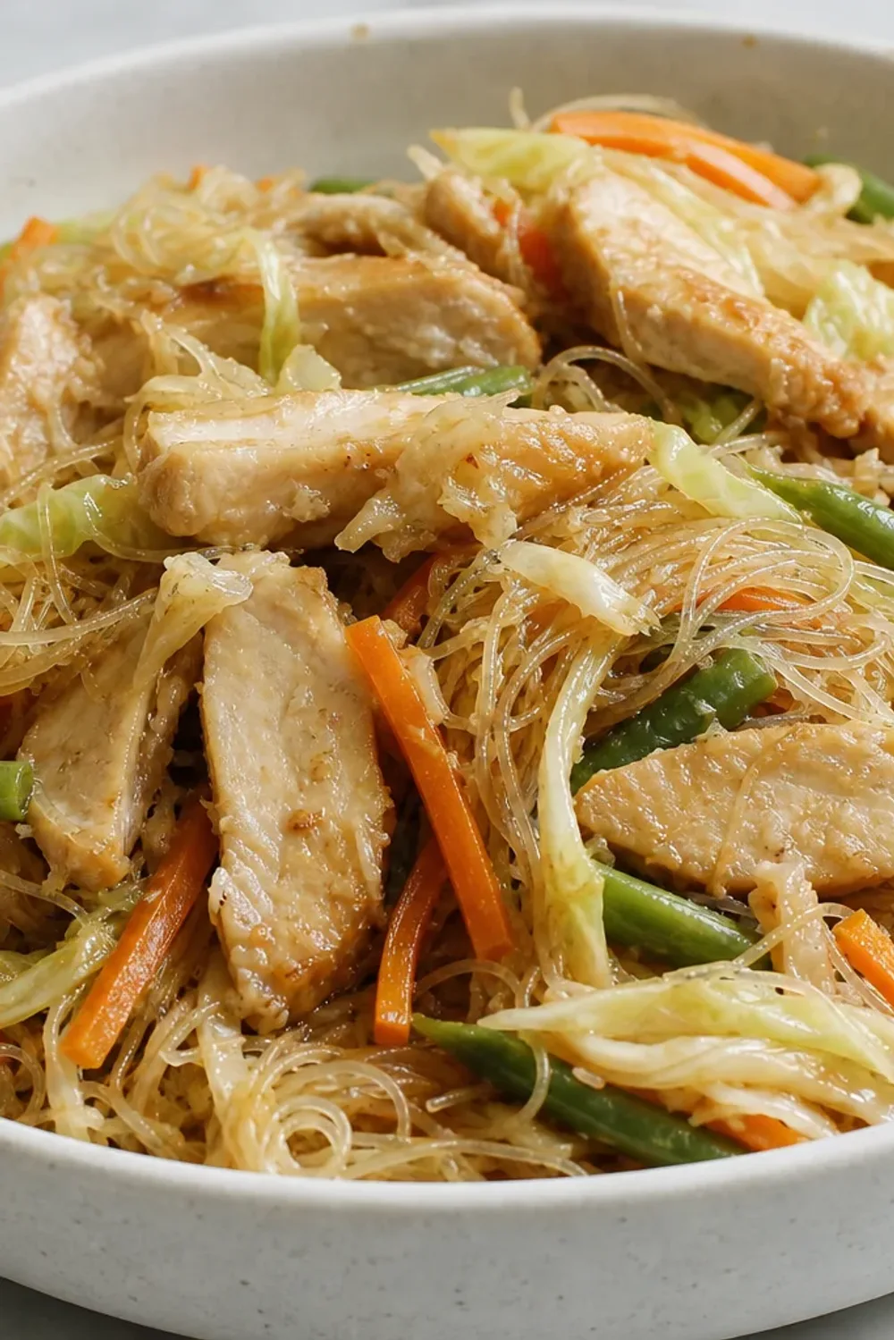 Stir-fried rice noodles topped with chicken and vibrant vegetables, garnished with green onions.