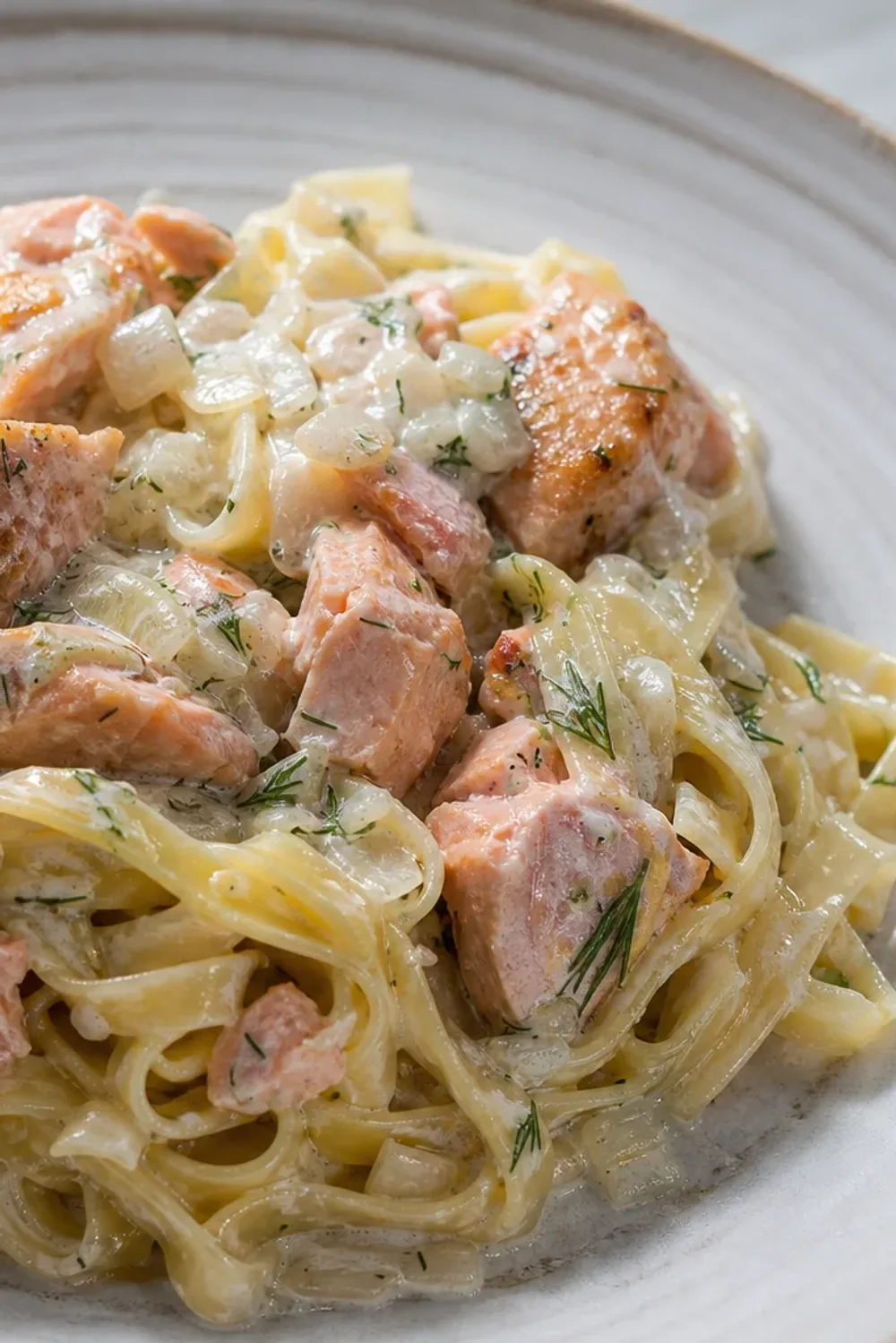 Creamy salmon pasta garnished with fresh dill and garlic, beautifully plated.