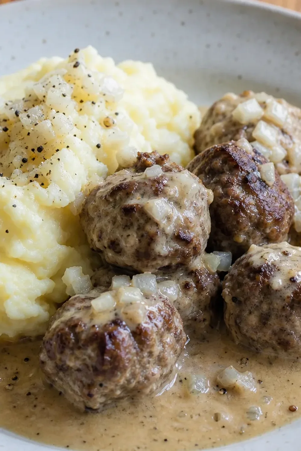 Tender Finnish meatballs smothered in creamy sauce, served with fluffy mashed potatoes and garnished with parsley.