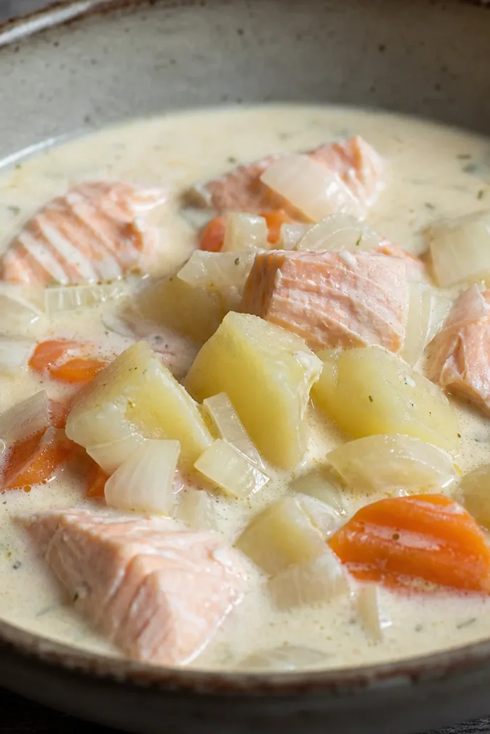 Creamy Finnish salmon soup with tender potatoes, carrots, and fresh herbs garnished elegantly in a bowl.