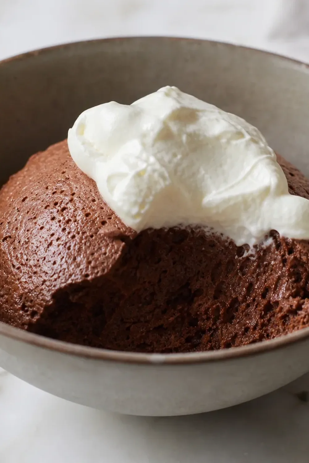 Smooth dark chocolate mousse topped with whipped cream and chocolate shavings, elegantly plated.