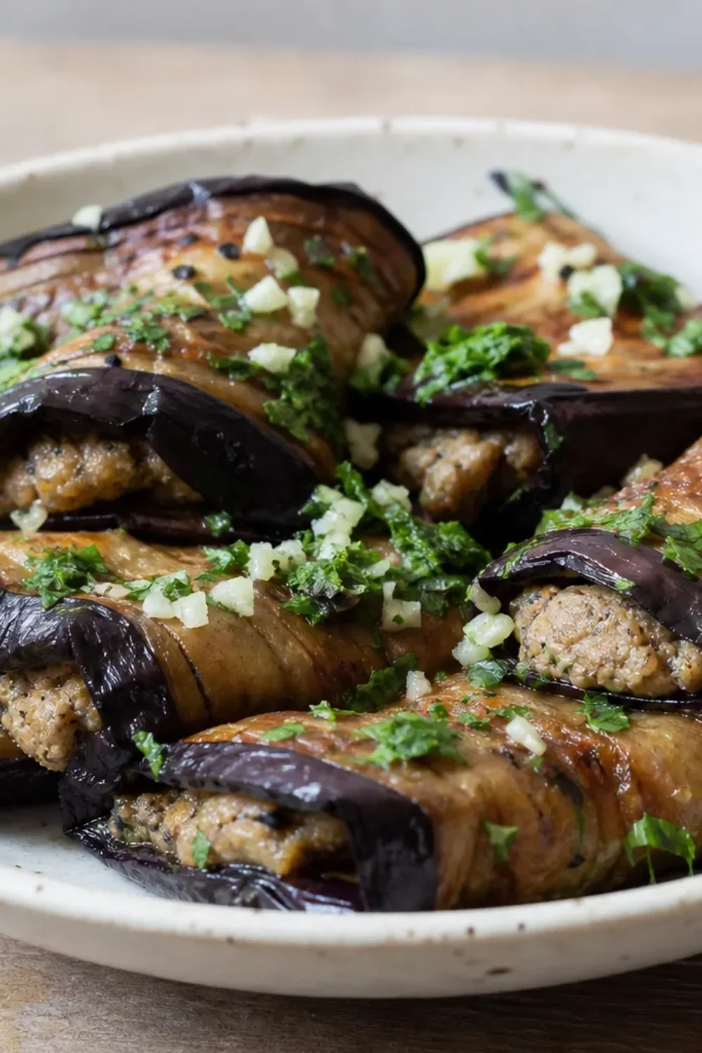 Elegant presentation of eggplant rolls filled with walnut paste, garnished with herbs.