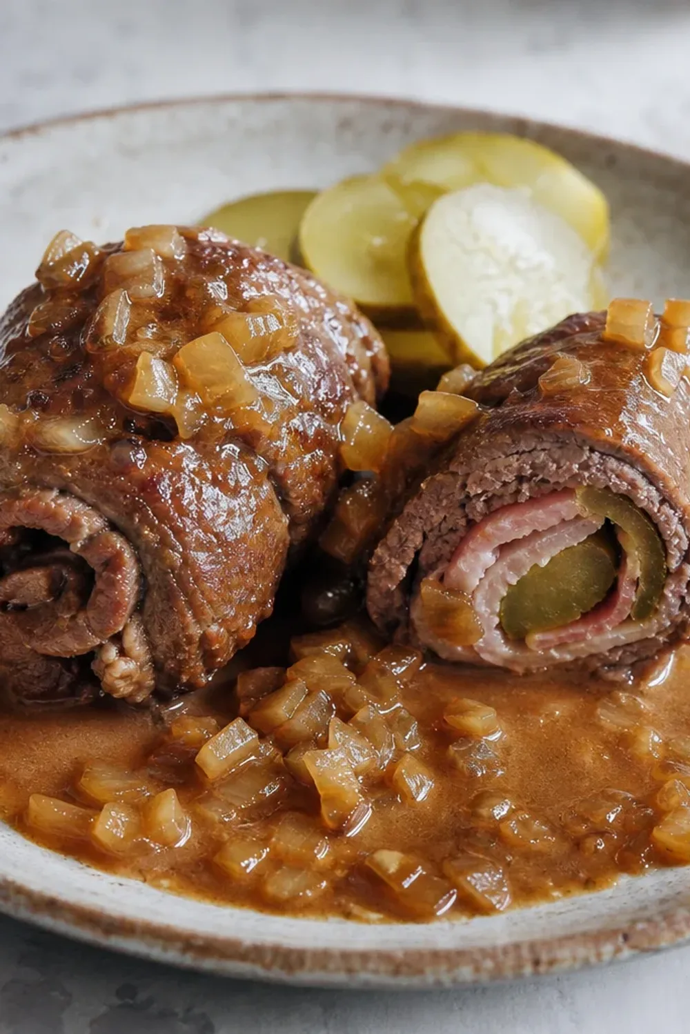 Tender beef rouladen filled with bacon and pickles, served with rich onion gravy.