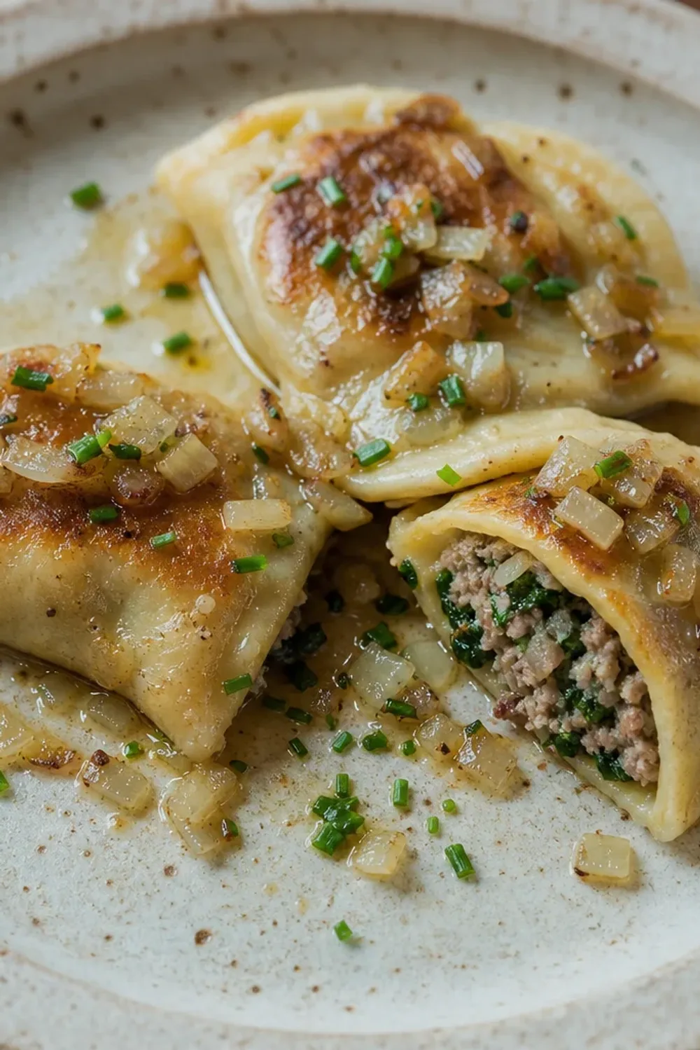 Plated German Maultaschen topped with brown butter and fresh herbs, golden and inviting.