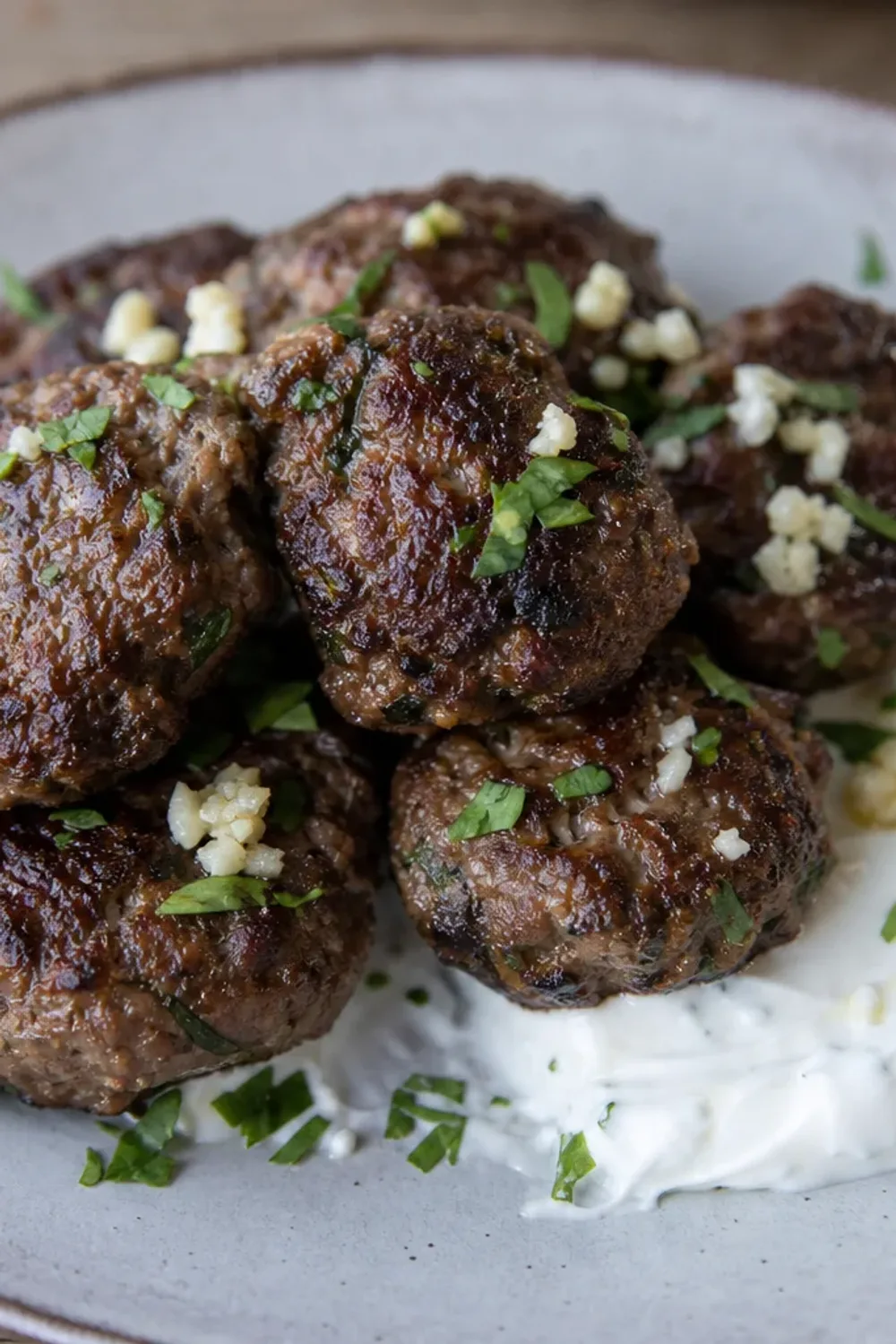 Crispy Greek keftedes garnished with herbs, served with garlic yogurt sauce on the side.