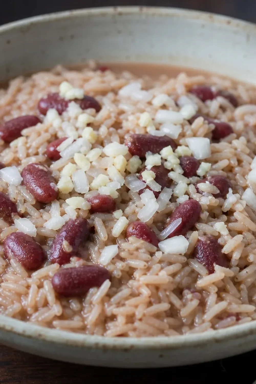 A vibrant plate of Haitian Diri Kole ak Pwa with fluffy rice, red beans, and fresh herbs garnishing the top.