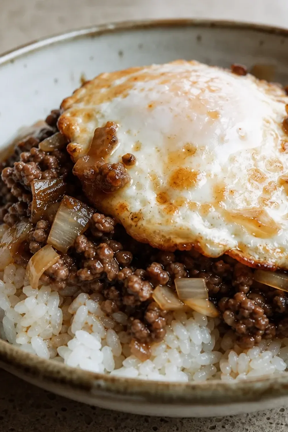 A hearty serving of Hawaiian loco moco with rice, a beef patty, brown gravy, and a perfectly fried egg on top.
