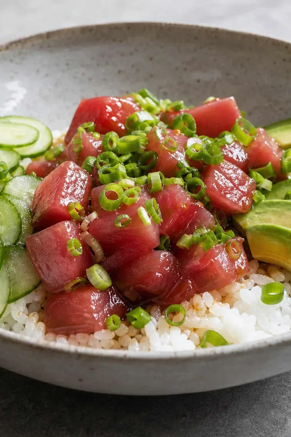 Colorful poke bowl featuring sliced ahi tuna, avocado, cucumber, and sesame seeds.