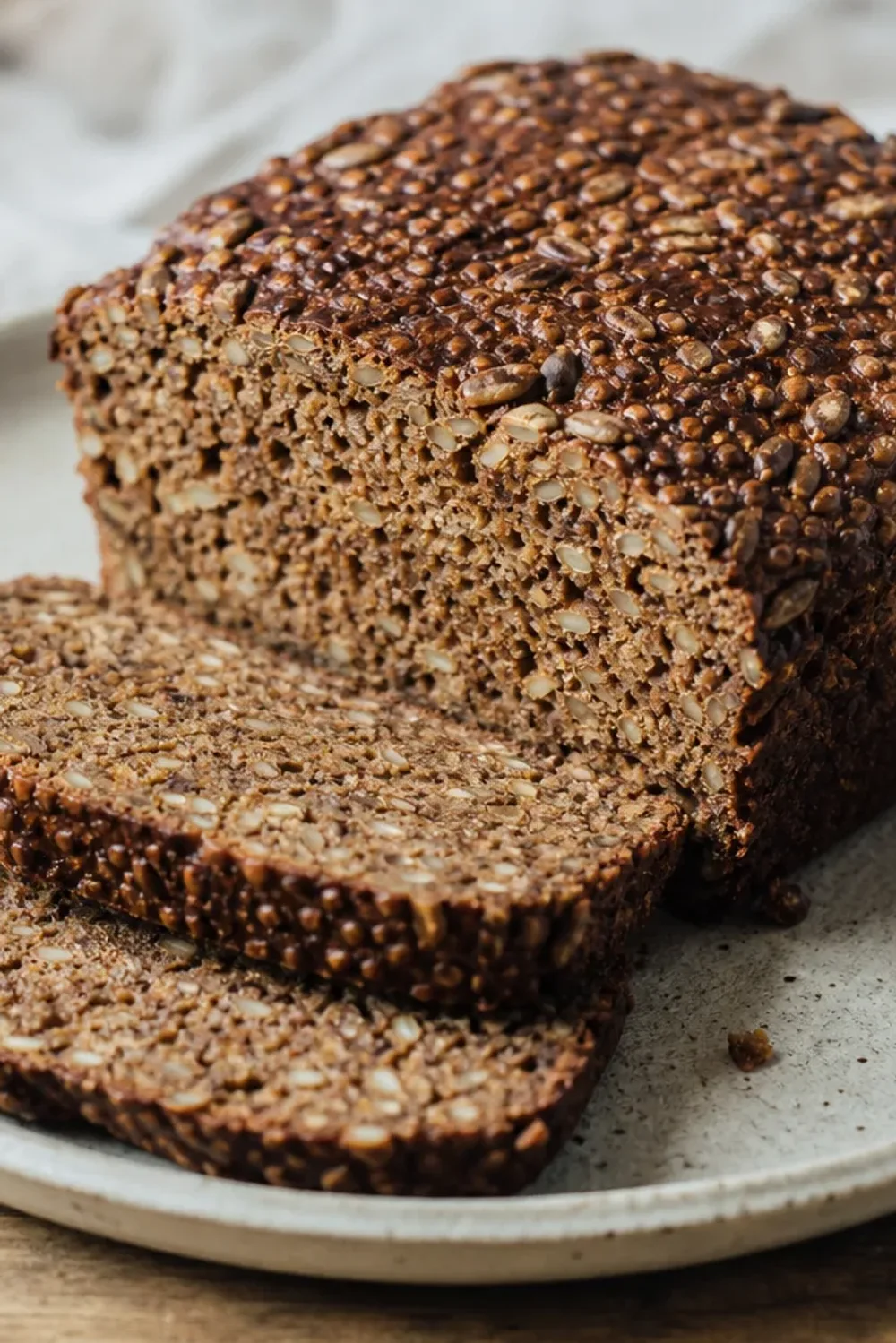 Sliced Danish Rugbrød showcasing the dense texture and seed toppings on a wooden board.