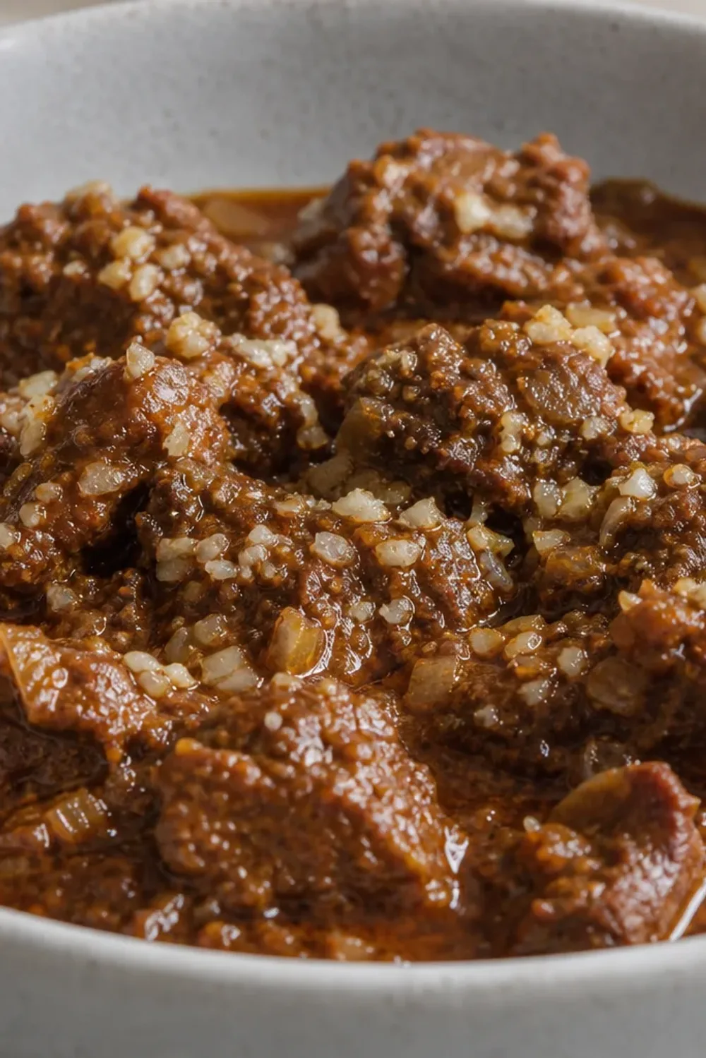 A bowl of Indian Lamb Rogan Josh garnished with fresh coriander and served with rice, showcasing tender lamb and rich red sauce.