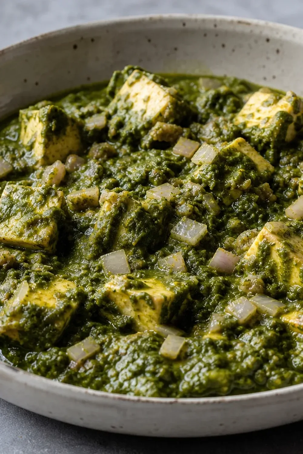 Vibrant green palak paneer served with soft paneer cubes and spices, garnished with cream.