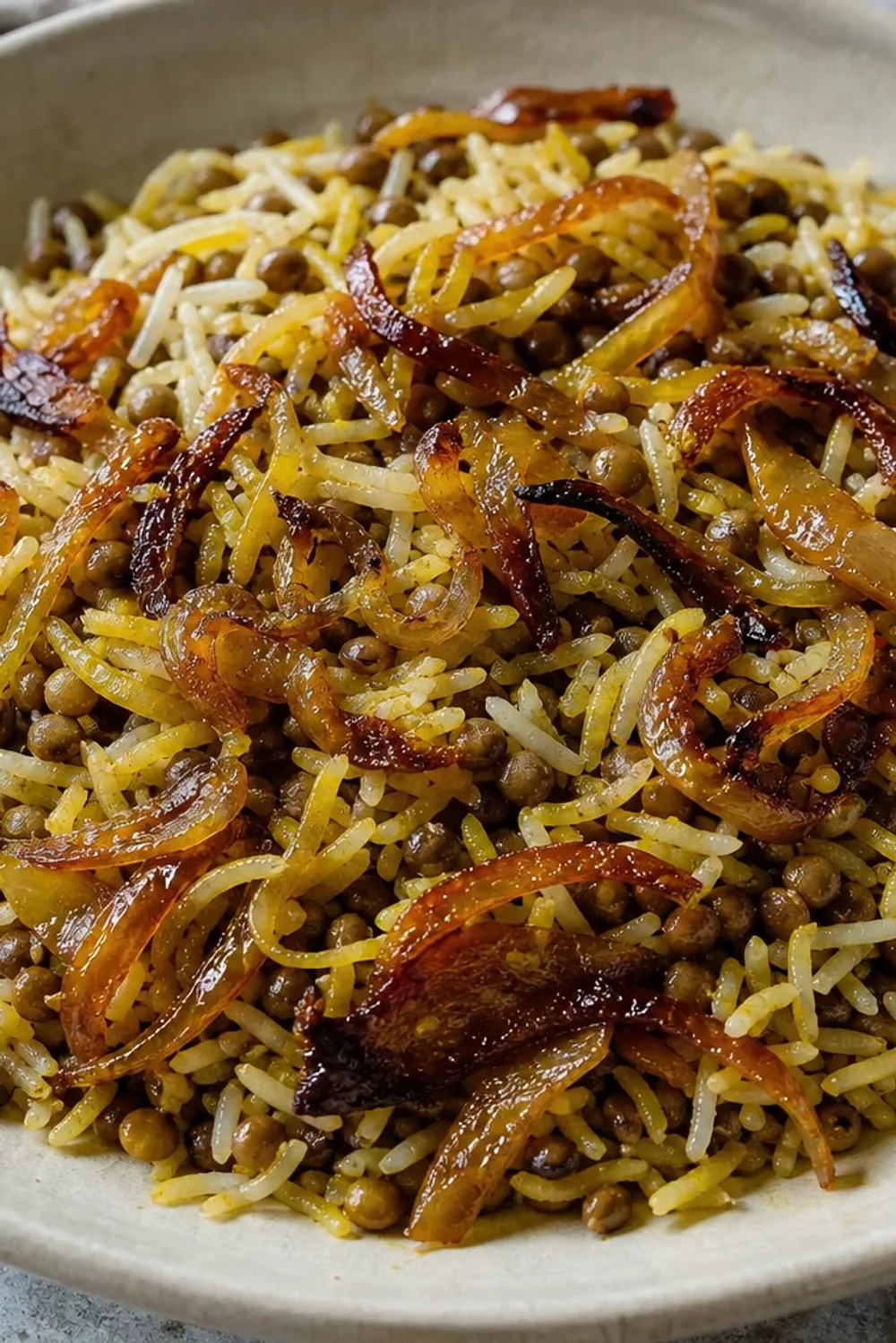 Fluffy rice layered with lentils and golden caramelized onions, garnished with herbs.