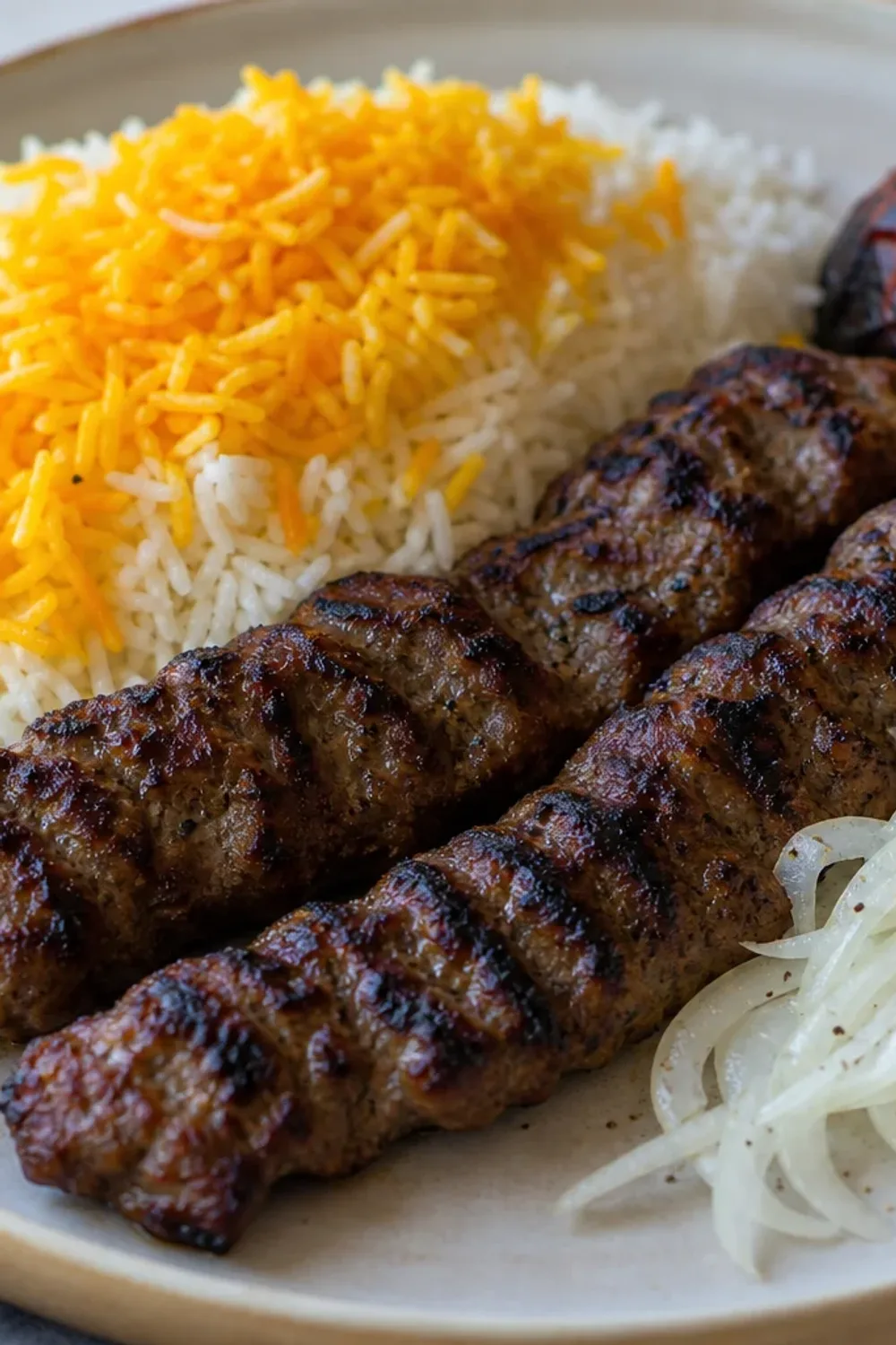 Plated Iranian Koobideh kebabs with saffron rice and colorful grilled vegetables, showcasing vibrant textures.