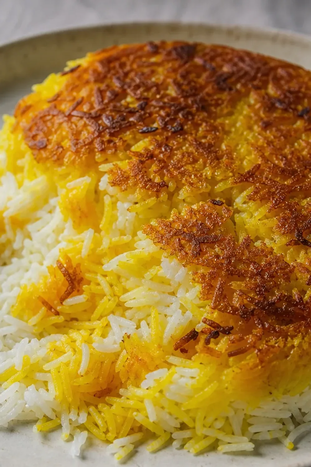 A plate of golden crispy tahdig with saffron rice, garnished with herbs and served with yogurt.