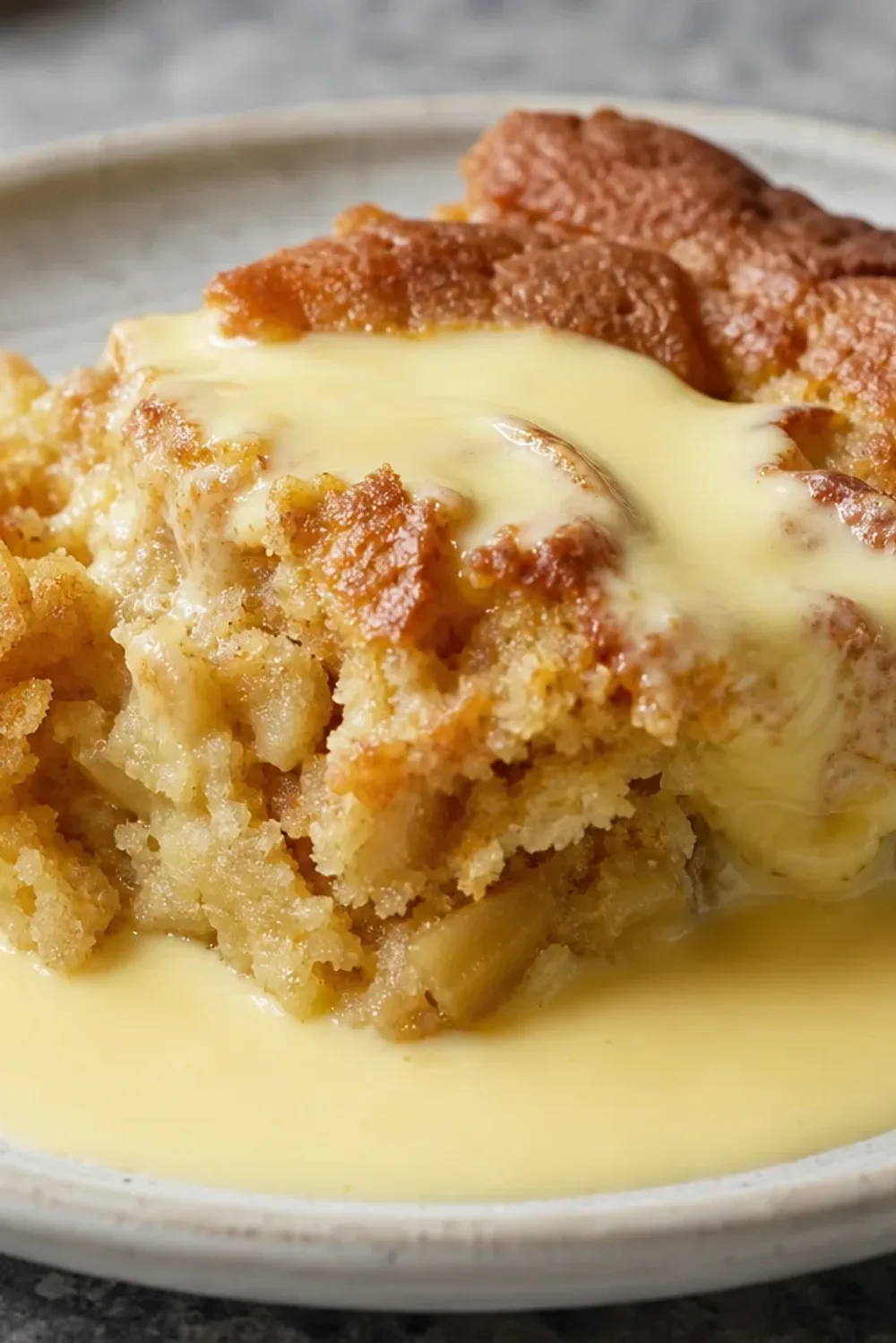 A slice of Irish apple cake topped with smooth custard sauce and fresh apple slices.