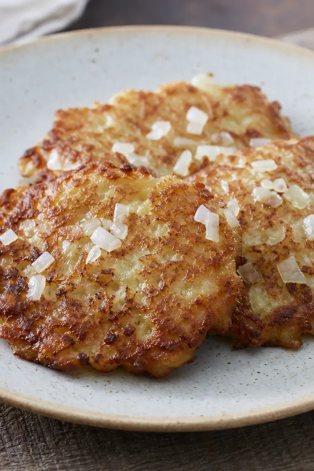 Golden-brown potato pancakes garnished with fresh herbs and served on a plate.