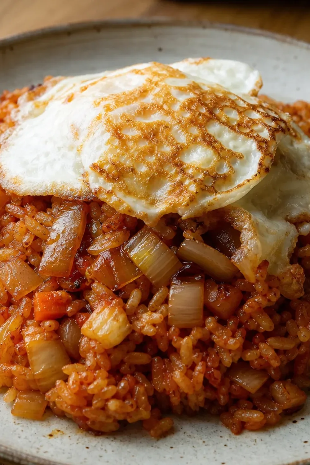 Colorful kimchi fried rice topped with a golden crispy egg and green onions.