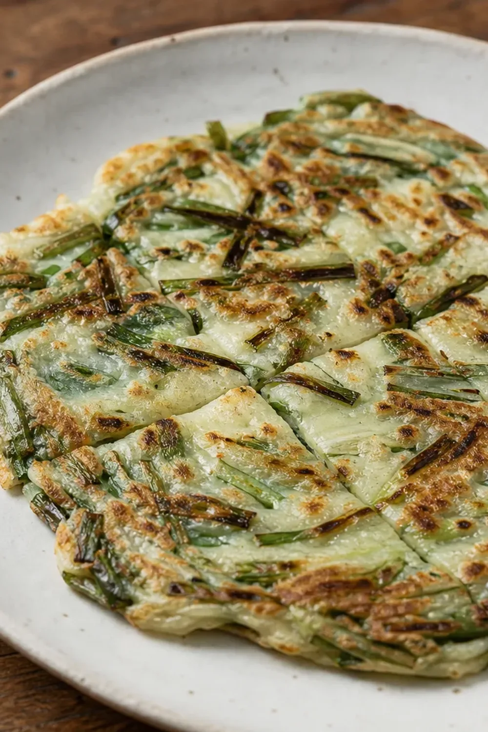 Golden-brown Korean pancakes topped with green scallions, served with a soy dipping sauce.
